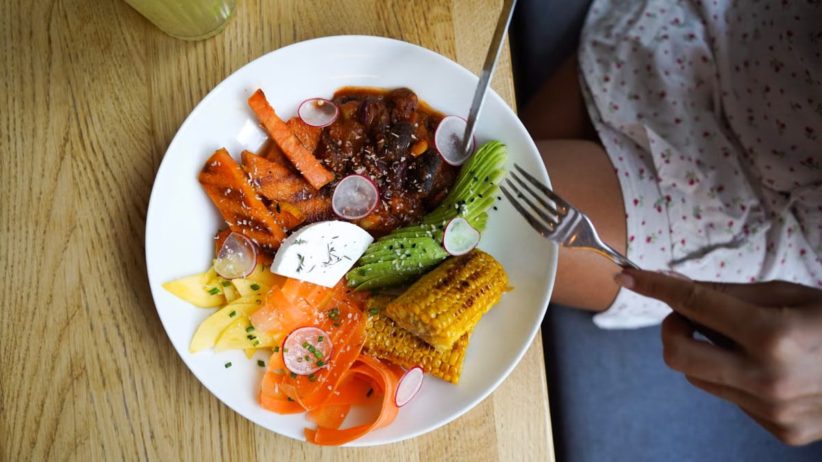 Colorful vegetarian meal with avocado, beans, and corn served on a wooden table. Ideal for healthy lifestyle visuals.